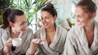 Drie jonge gelukkige vrouwen die thee drinken in een spa resort