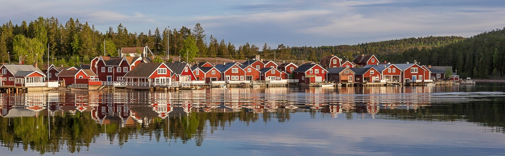 sarkanās mājas saulrietā zvejnieku ciematā Norfaellsviken, Höga Kusten, Zviedrija