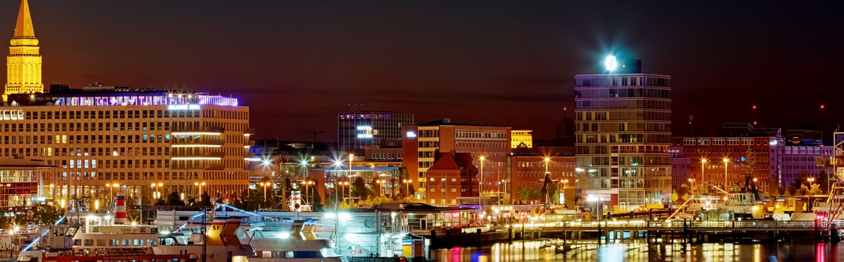 The waterscape of Kiel Harbour at night  with the lights of the ships and buildings reflected in the calm waters.