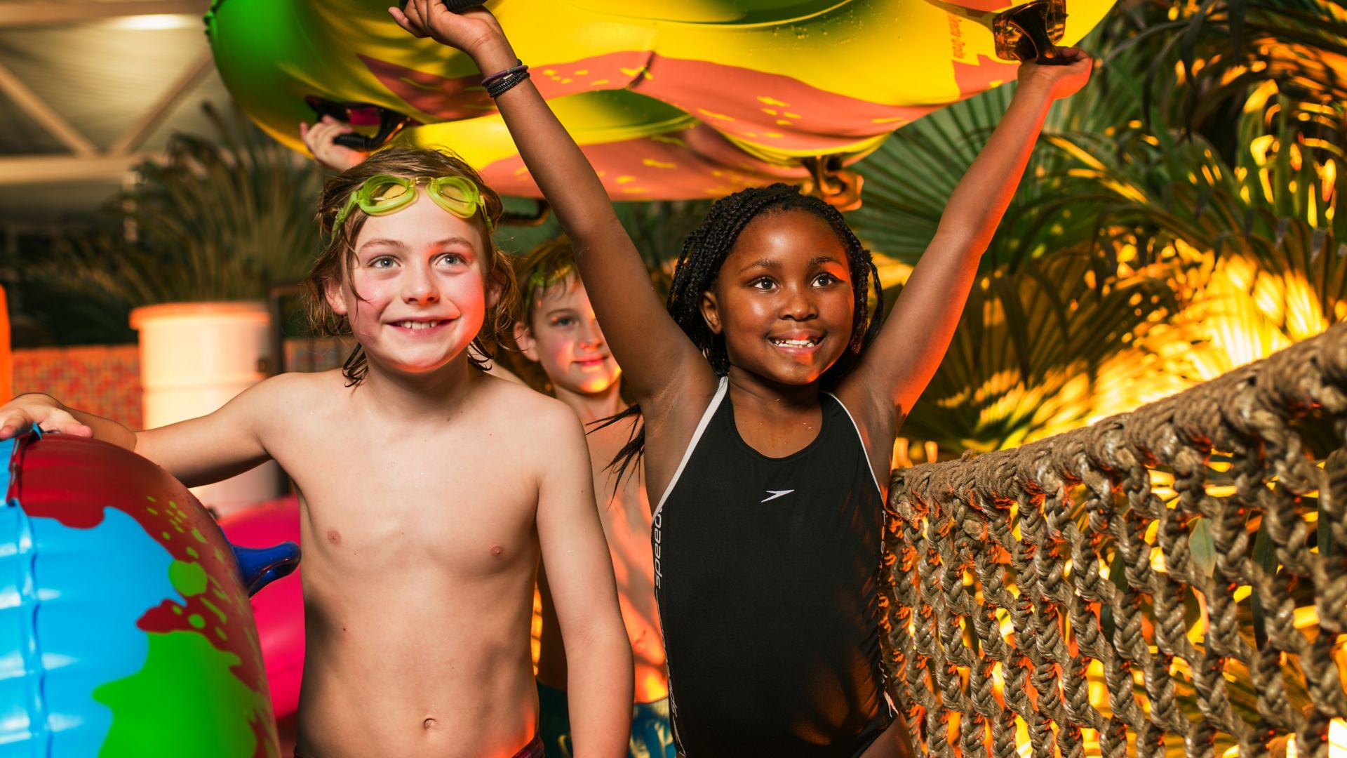 Children carrying water rafts over a rope bridge at the indoor pool at the Reef Resort