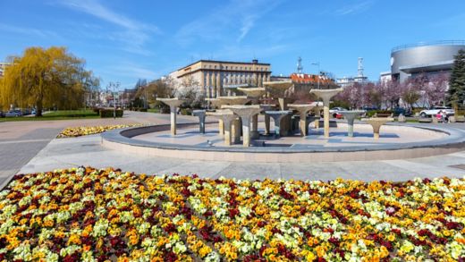  Kosciuszko-torget i Gdynia med stenskulpturer, ljusa blommor och kommunistisk arkitektur.