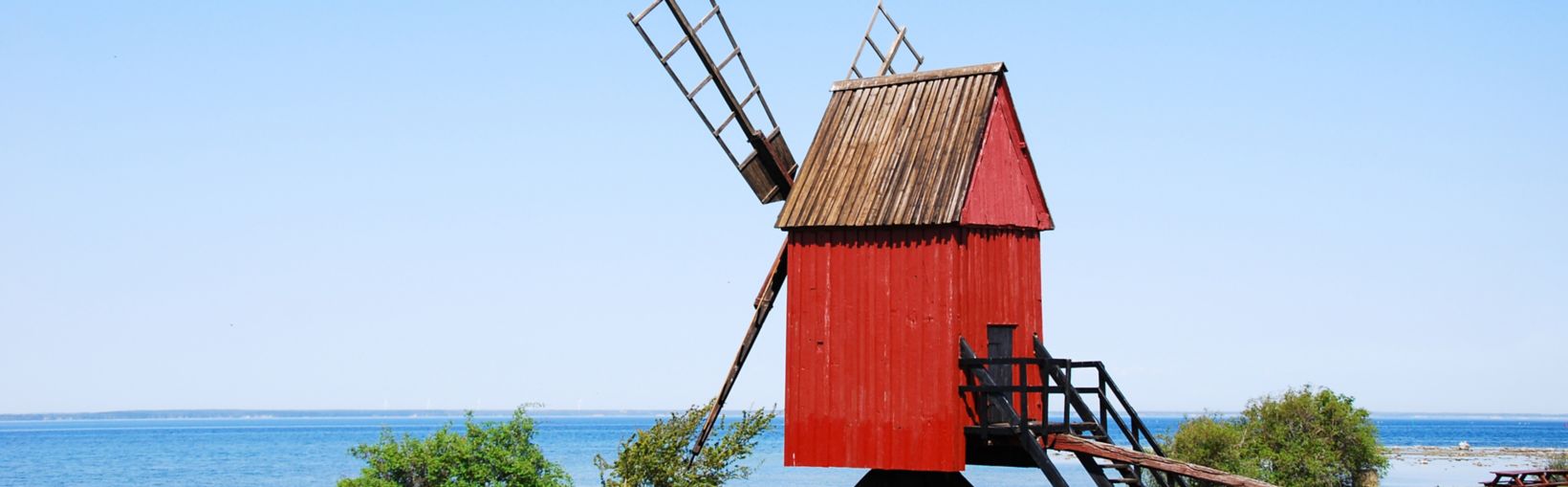 Viejo molino de viento tradicional de madera de color rojo junto a la costa de la isla sueca de Öland