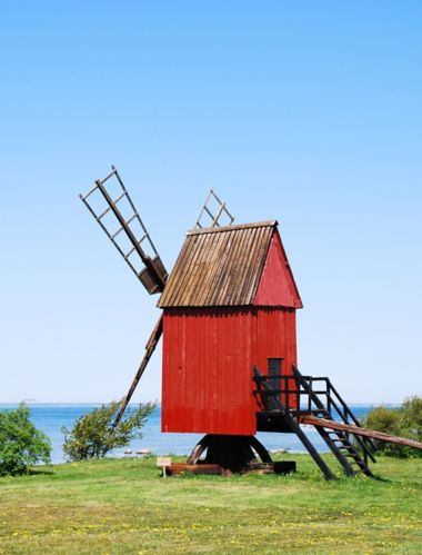 Senas raudonos spalvos, mažas medinis tradicinis vėjo malūnas prie Švedijos Elando salos pakrantės