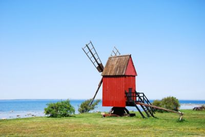 Mały, stary, tradycyjny, drewniany wiatrak pomalowany na czerwono na wybrzeżu szwedzkiej wyspy Olandii