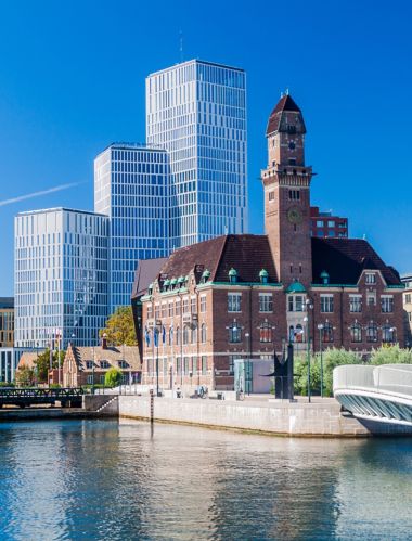 Miejski krajobraz Malmö w Szwecji z widokiem na stare i nowoczesne budynki na tle czystego, niebieskiego nieba