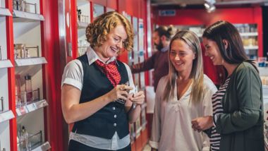 Glimlachende vrienden testen parfum met personeelslid in de winkel