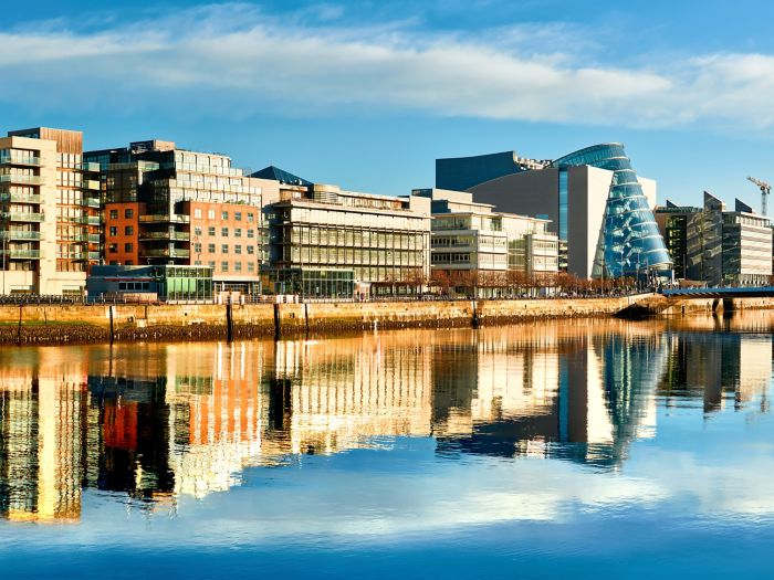 Modern buildings and offices on Liffey river in Dublin on a bright sunny day, with Harp bridge on the right