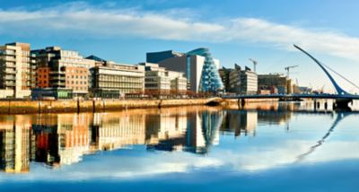 Modern buildings and offices on Liffey river in Dublin on a bright sunny day, with Harp bridge on the right
