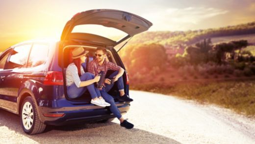 A couple sitting in the back of a car enjoying a sunset