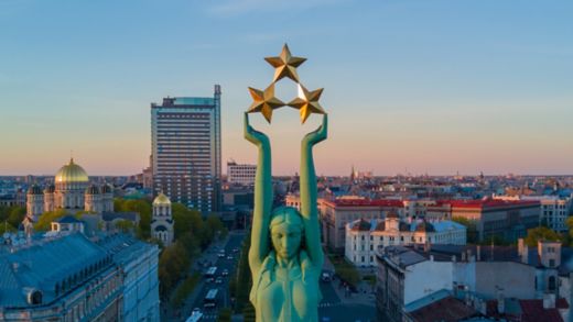 Herrlicher Blick auf den Sonnenuntergang in Riga bei der Freiheitsstatue – Milda. Freiheit in Lettland. Freiheitsstatue mit drei Sternen in den Händen, die sie über die Stadt hält.