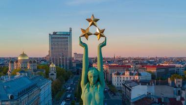Hermosa vista del atardecer en Riga junto a la Estatua de la Libertad - Milda. Libertad en Letonia. Estatua de la Libertad sosteniendo tres estrellas sobre la ciudad.