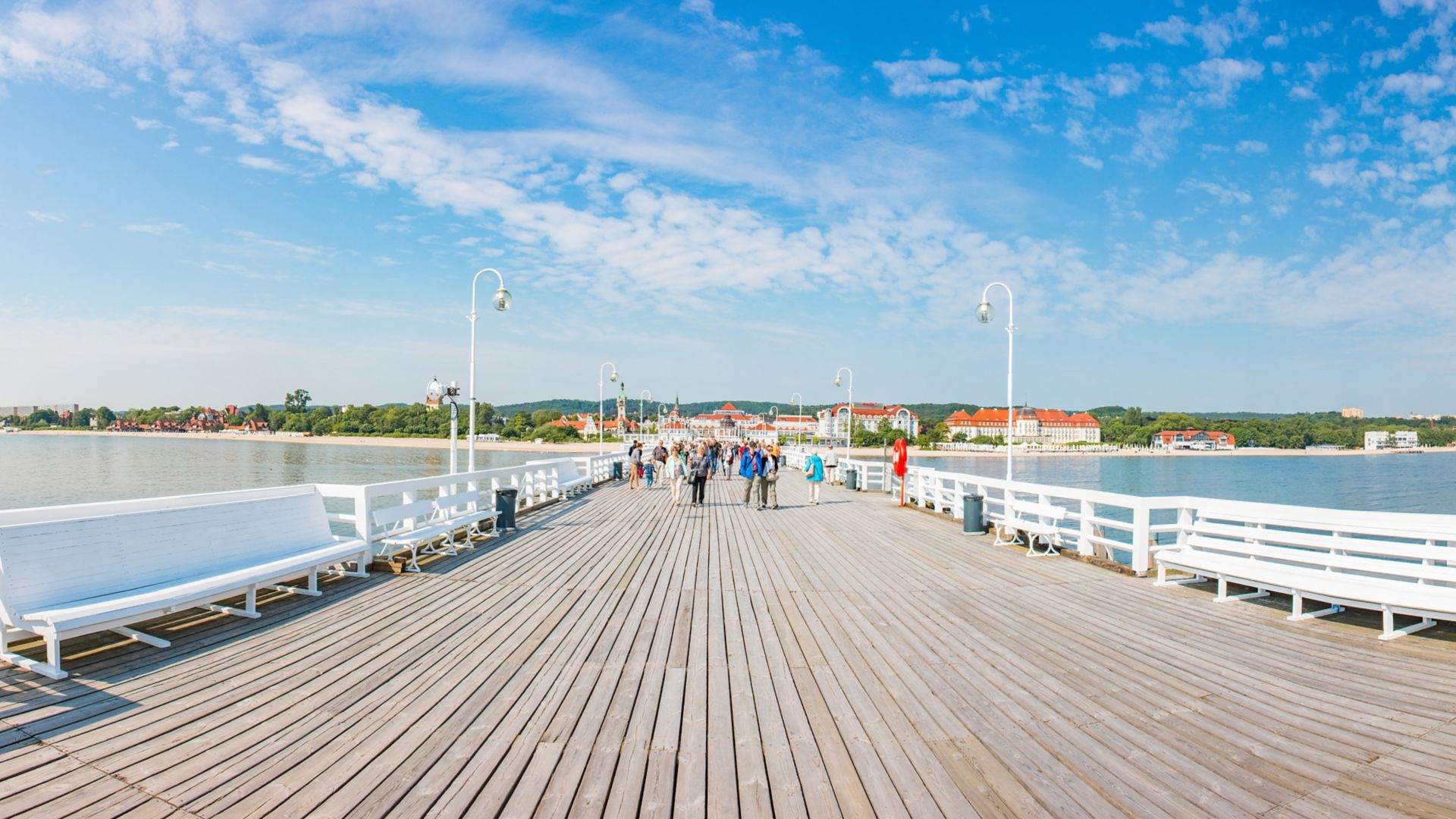 Pohled na lidi chodící za slunečného dne po mole v Sopotech v Gdyni, Polsko