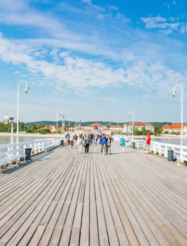 Skats ar cilvēkiem, kuri saulainā dienā staigā pa Sopotas molu Gdiņā, Polija