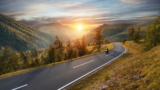 Motorcycle driver riding in Alpine highway,  Nockalmstrasse, Austria, Europe. Outdoor photography, mountain landscape. Travel and sport photography. Speed and freedom concept