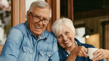 Een ouder echtpaar dat glimlacht terwijl zij van een koffie aan boord genieten
