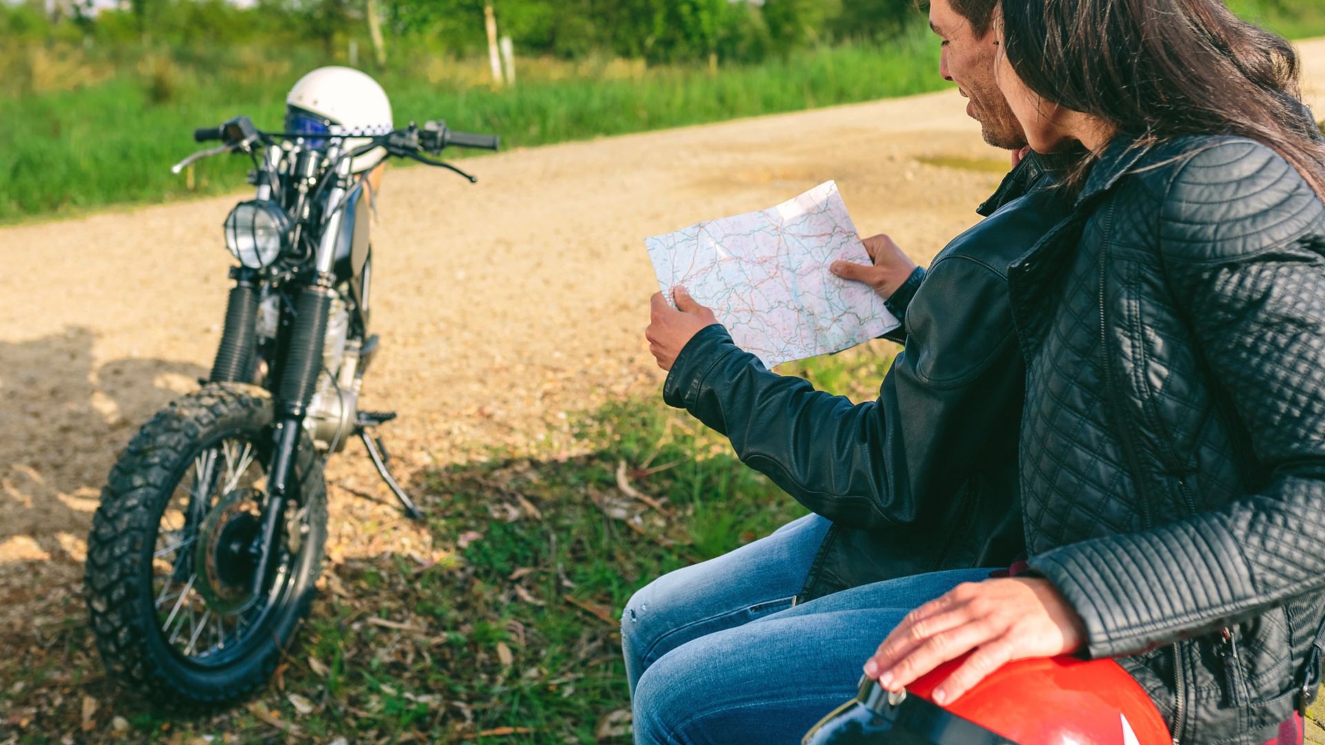 Young couple sitting looking at a map during a motorcycle trip