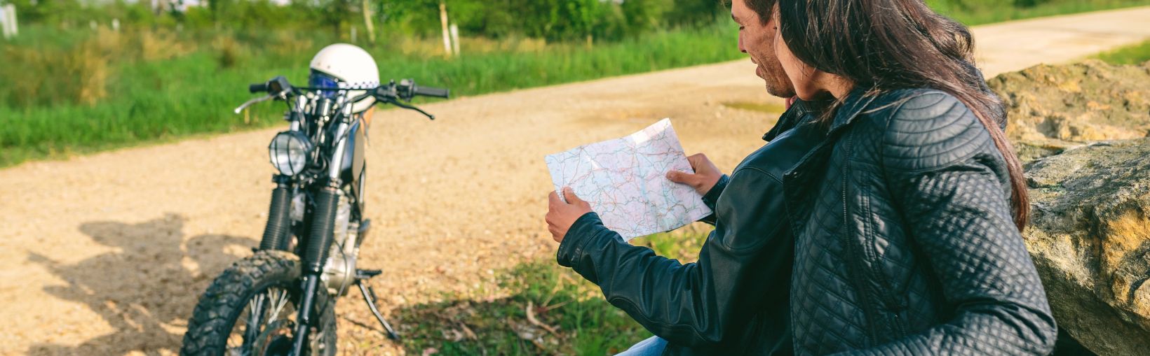 Young couple sitting looking at a map during a motorcycle trip