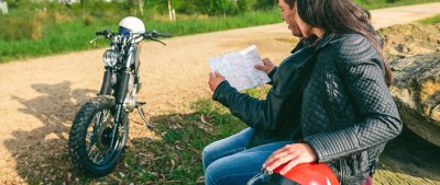 Young couple sitting looking at a map during a motorcycle trip