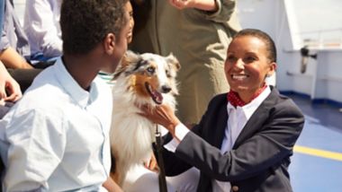 Female staff member chats to a family travelling with their dog on the outer deck of a Stena Line ferry