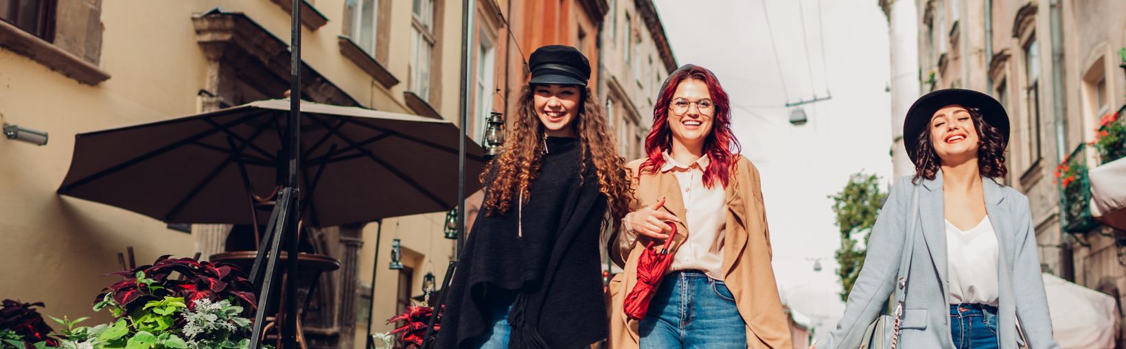 Photo extérieure de trois jeunes femmes marchant dans la rue de la ville.