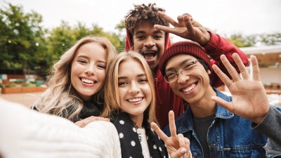 Group of cheerful friends teenagers spending fun time together outdoors, taking a selfie