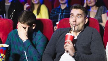 Young men watching a scary movie at the cinema