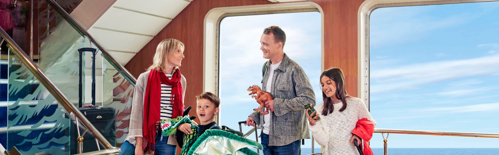 Familia llevando equipaje y un dragón subiendo escaleras a su cabina en un ferry 
