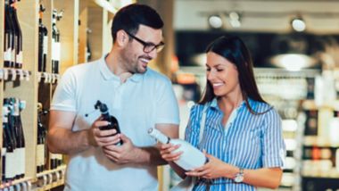 Happy couple shopping in supermarket buying wines