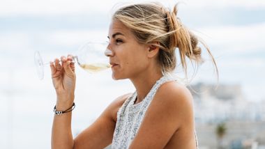 Vrouw drinkt witte wijn uit een glas terwijl ze uitkijkt op zee vanaf de Deck Bar aan boord van een ferry