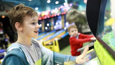 Boys playing arcade game in amusement park