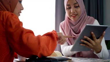 Young friends smiling and looking at their tablet device while using free Wi-Fi onboard a ferry