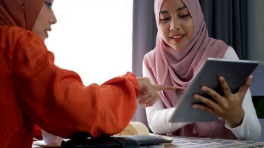 Young friends smiling and looking at their tablet device while using free Wi-Fi onboard a ferry