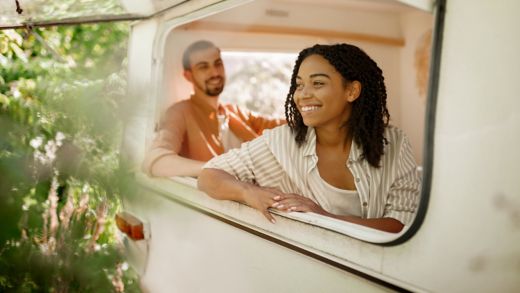Husband and wife looks out of rv window, camping in a trailer. Man and woman travels on van, romantic vacations on motorhome, campers leisures in camping-car