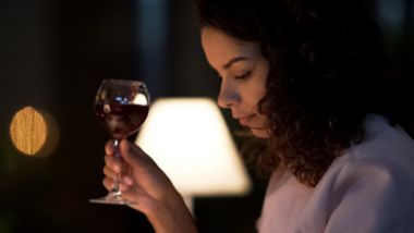 Femme buvant du vin dans le bar à bord, rédigeant un message sur son smartphone.