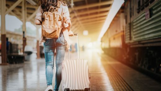 Woman traveler tourist walking with luggage at train station. Active and travel lifestyle concept