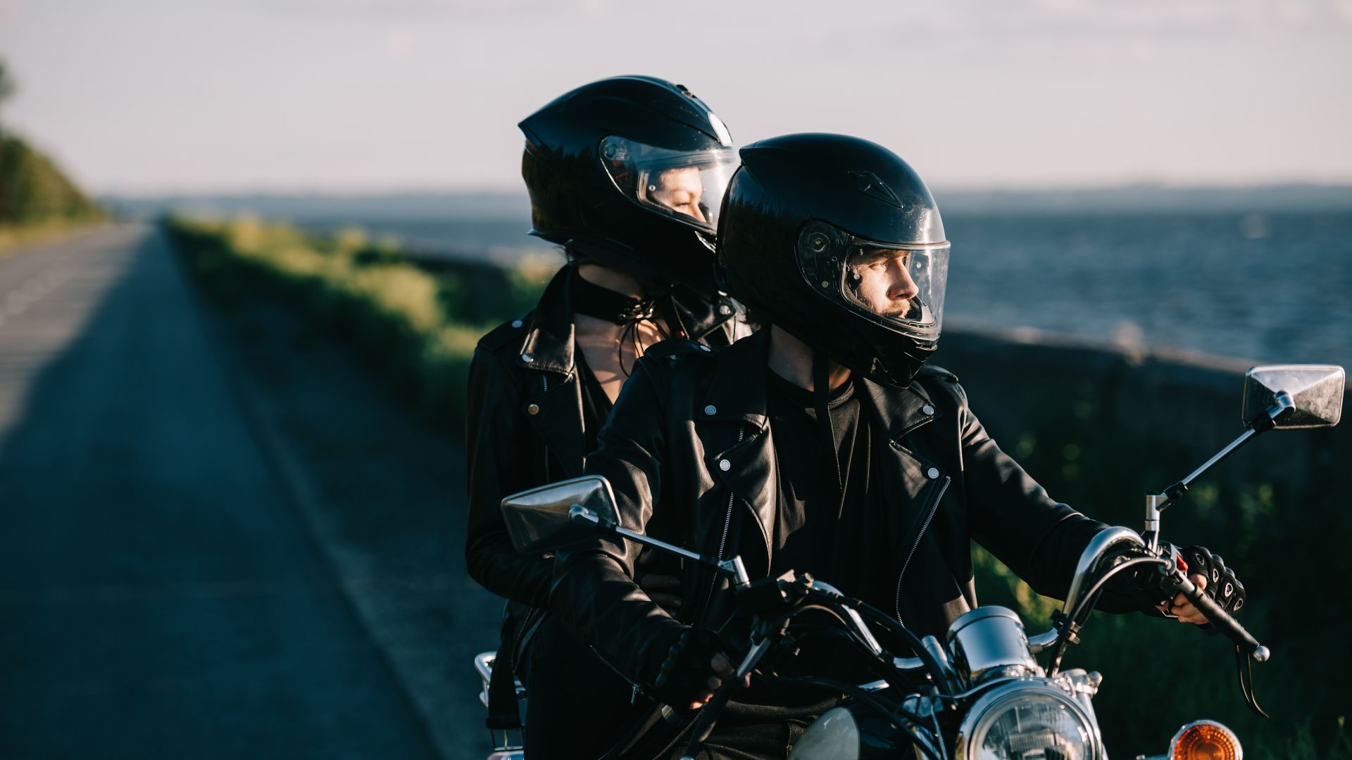 couple of bikers in helmets riding classical motorcycle on country road