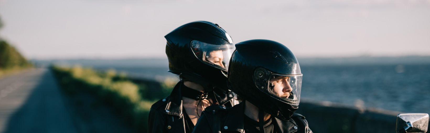 couple of bikers in helmets riding classical motorcycle on country road