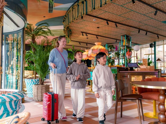 Smiling family arriving at Quality Hotel The Reef in Frederikshavn’s colourful tropical-themed lobby