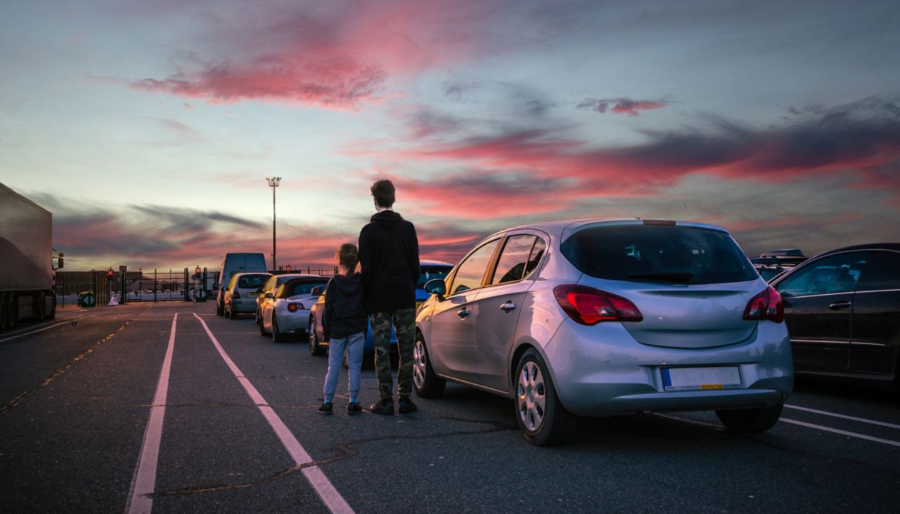 Broers en zussen die naast hun auto staan, kijkend naar de zonsondergang terwijl ze wachten om aan boord te gaan van een Stena Line ferry