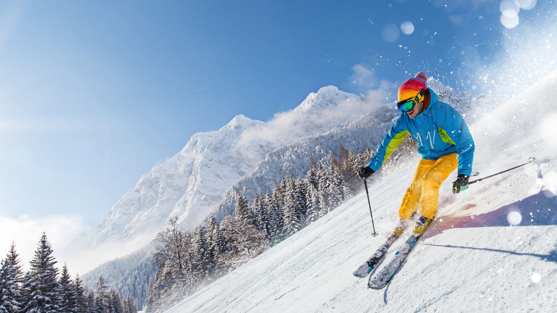 Sciatore che scia in discesa durante la giornata di sole sulle alte montagne