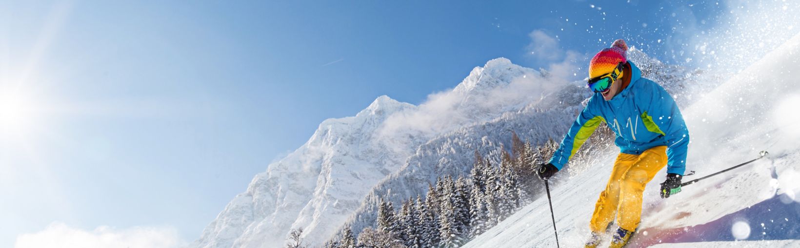 Skier skiing downhill during sunny day in high mountains