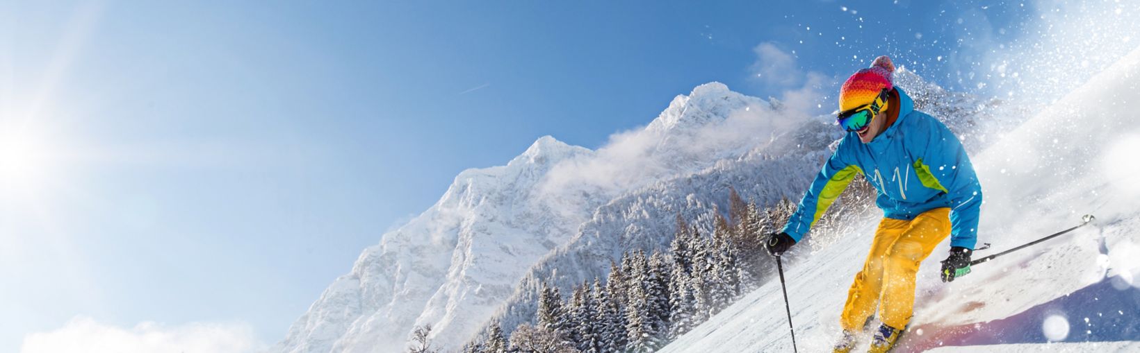 Sciatore che scia in discesa durante la giornata di sole in alta montagna