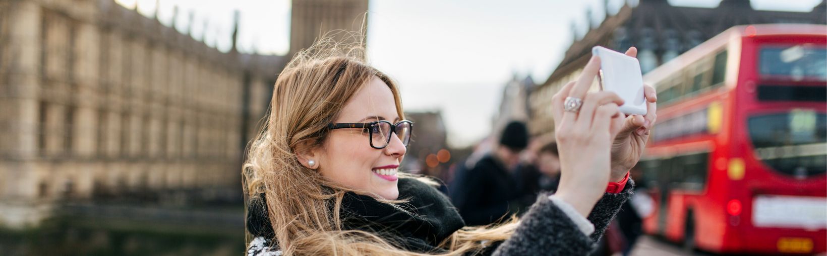 Vrouw neemt selfie in Londen naast Houses of Parliament en een rode dubbeldekker bus