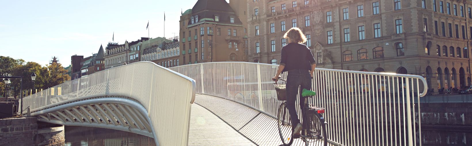 Per tiltą dviračiu važiuojanti moteris 