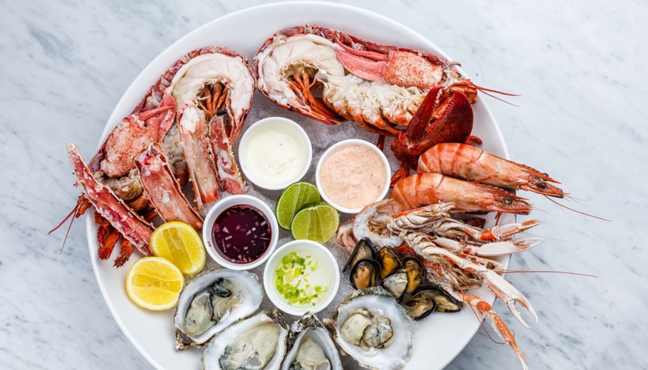 Plateau de fruits de mer frais avec homard, moules et huîtres sur une table en marbre.