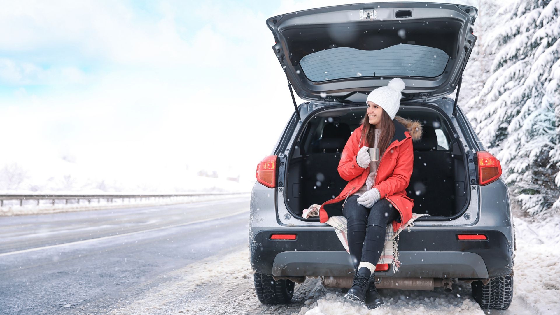 Female tourist drinking tea near car in snowy countryside