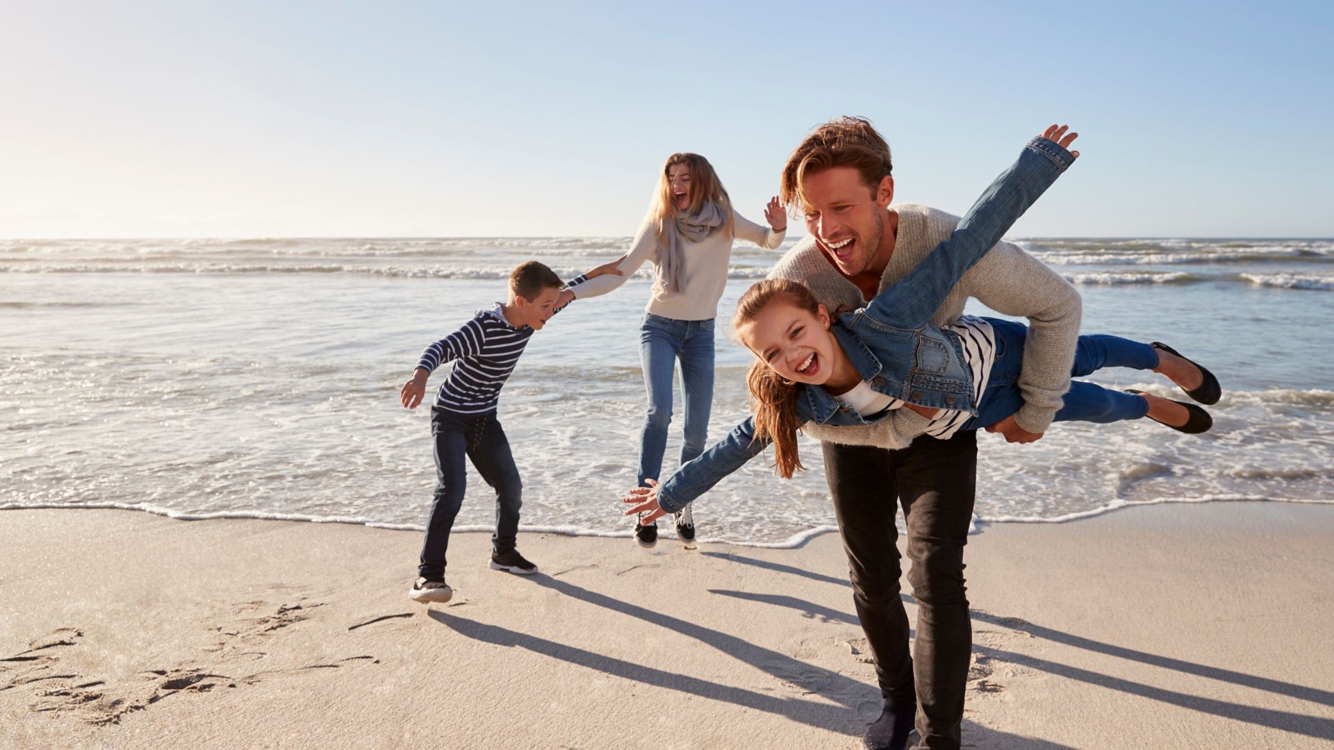 Parents With Children Having Fun On Winter Beach Together