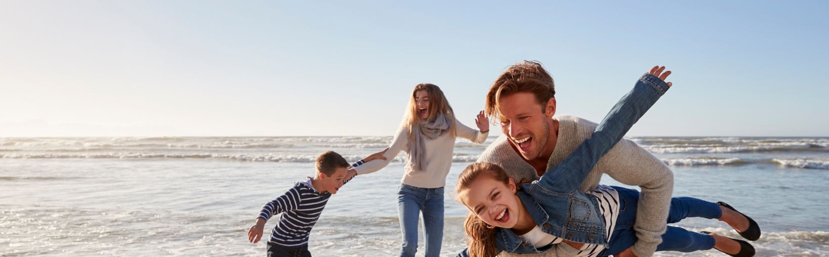 Parents With Children Having Fun On Winter Beach Together