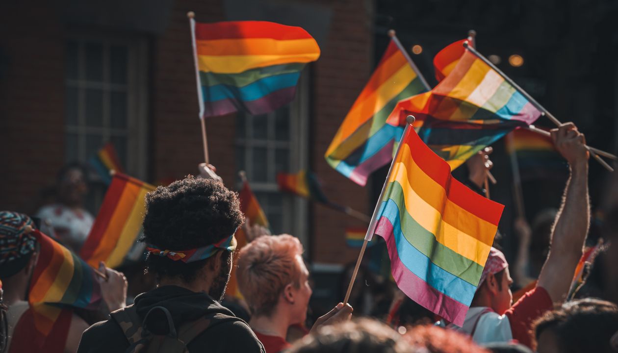 Nierozpoznawalny podświetlony tłum z tęczowymi flagami i znakami w corocznej Paradzie Równości, gdy przechodzi przez Greenwich Village.