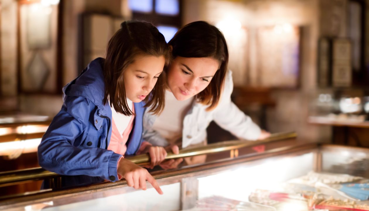 Glad mor och dotter som besöker utställningar med teman från tidigare århundraden på museum